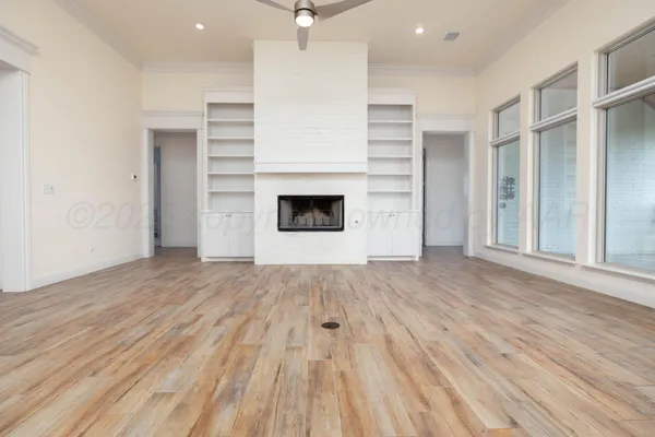 an empty room with wooden floor a fireplace and windows