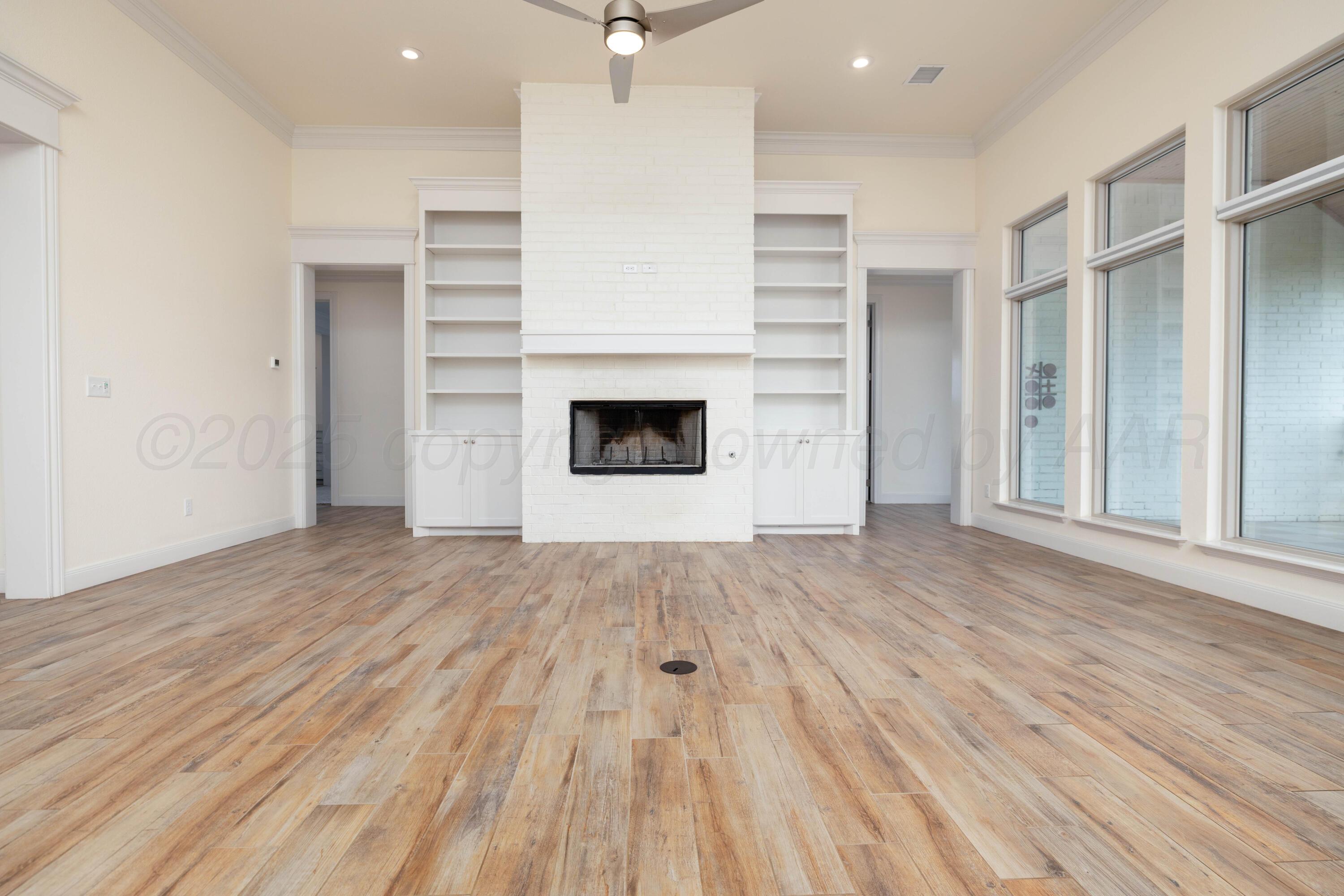 19350 Falcon Ridge Road Amarillo, TX 79124 - Photo 9 of 41 an empty room with wooden floor a fireplace and windows