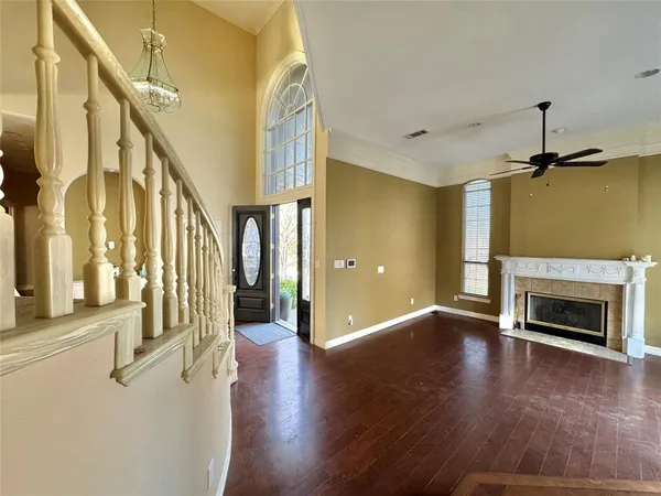 a view of an empty room with wooden floor fireplace and a window