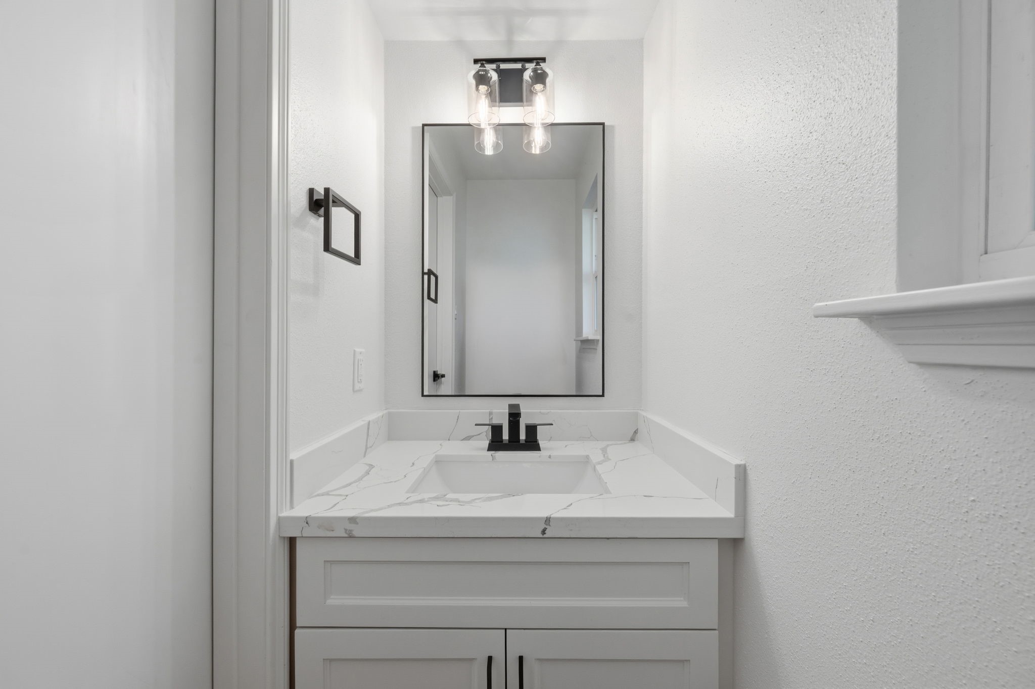 210 Ridgemont Drive Alvin, TX 77511 - Photo 11 of 27 Compact and modern bathroom with a marble countertop, sleek black fixtures, and a stylish vanity mirror. The white walls and ample lighting create an open, fresh feel.