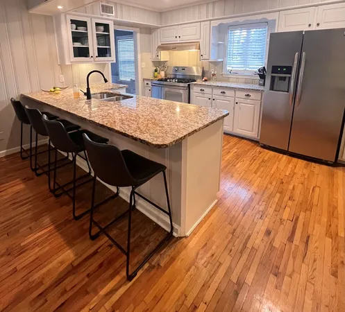 a kitchen with granite countertop a stove a sink and a refrigerator