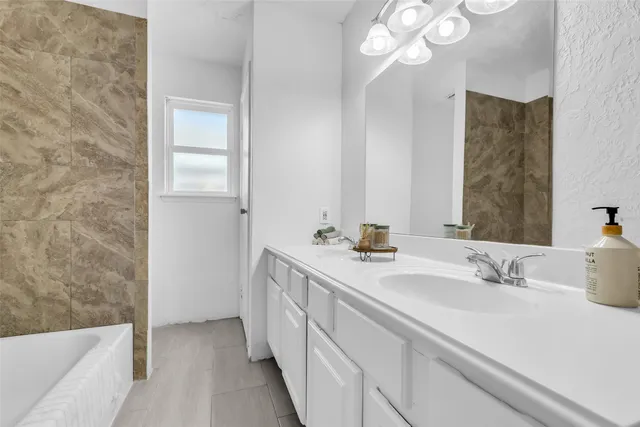 a bathroom with a sink a large mirror and a bathtub