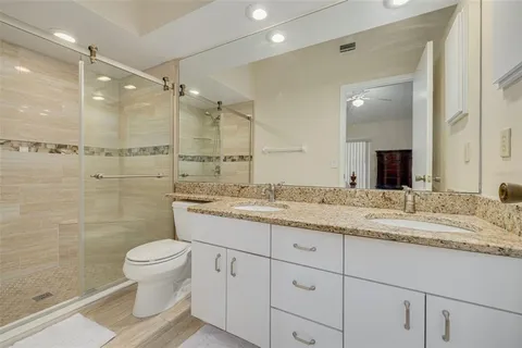 a bathroom with a granite countertop sink a toilet and shower