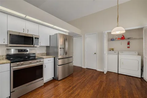 a kitchen with a refrigerator stove and wooden floor