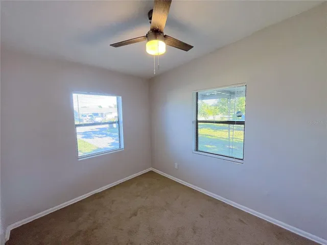 an empty room with a window and a ceiling fan