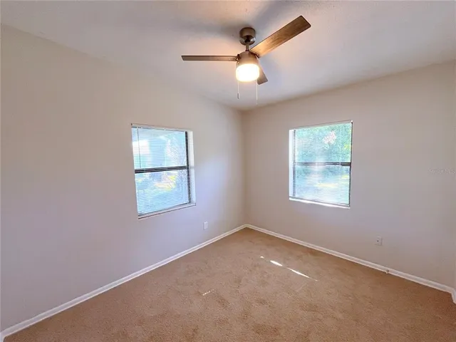 an empty room with a fan & a window