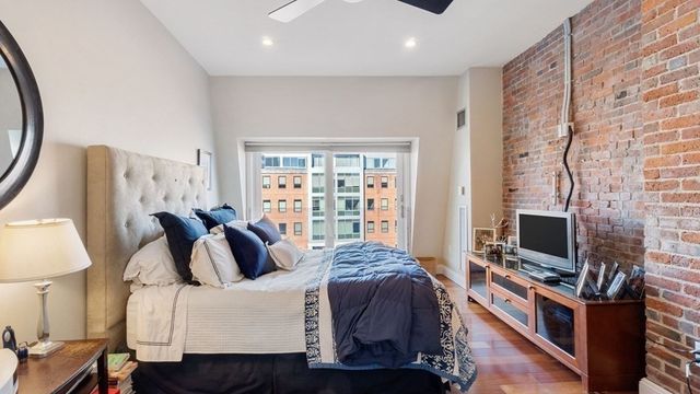 a bedroom with a bed a couch and a flat tv screen on the dresser