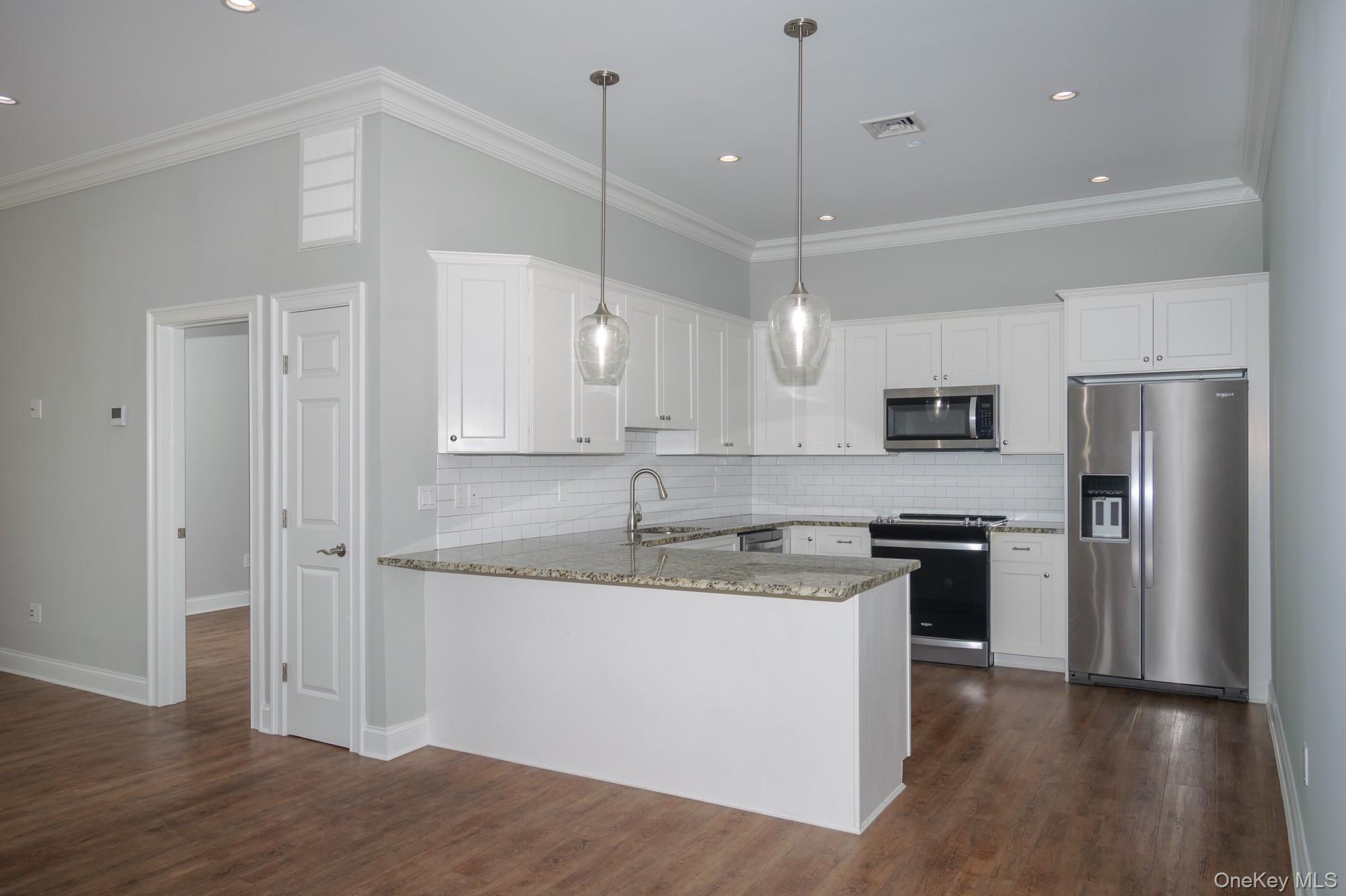 2 Union Place, Unit 3F Huntington, NY 11743 - Photo 2 of 11 a kitchen with stainless steel appliances granite countertop a sink a stove a refrigerator and island with wooden floor