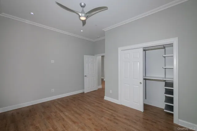 an empty room with wooden floor and ceiling fan