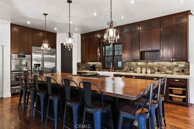 a kitchen with granite countertop a table chairs stainless steel appliances and cabinets