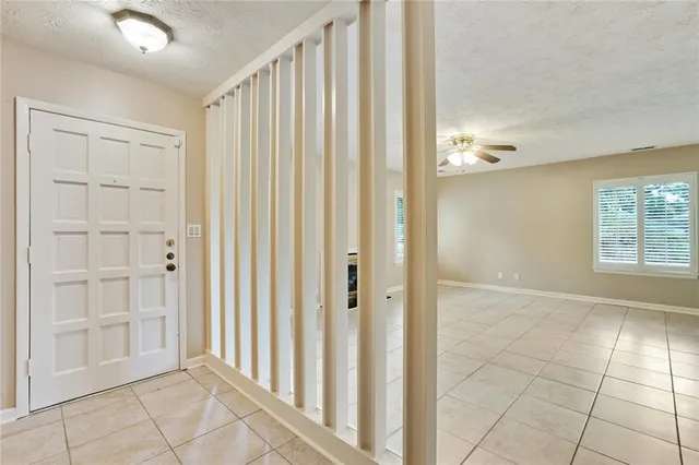 an empty room with chandelier fan and windows