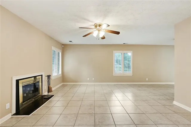 a view of an empty room with window and chandelier fan