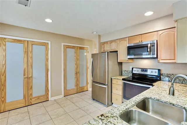 a kitchen with stainless steel appliances granite countertop a refrigerator a stove a sink and a microwave