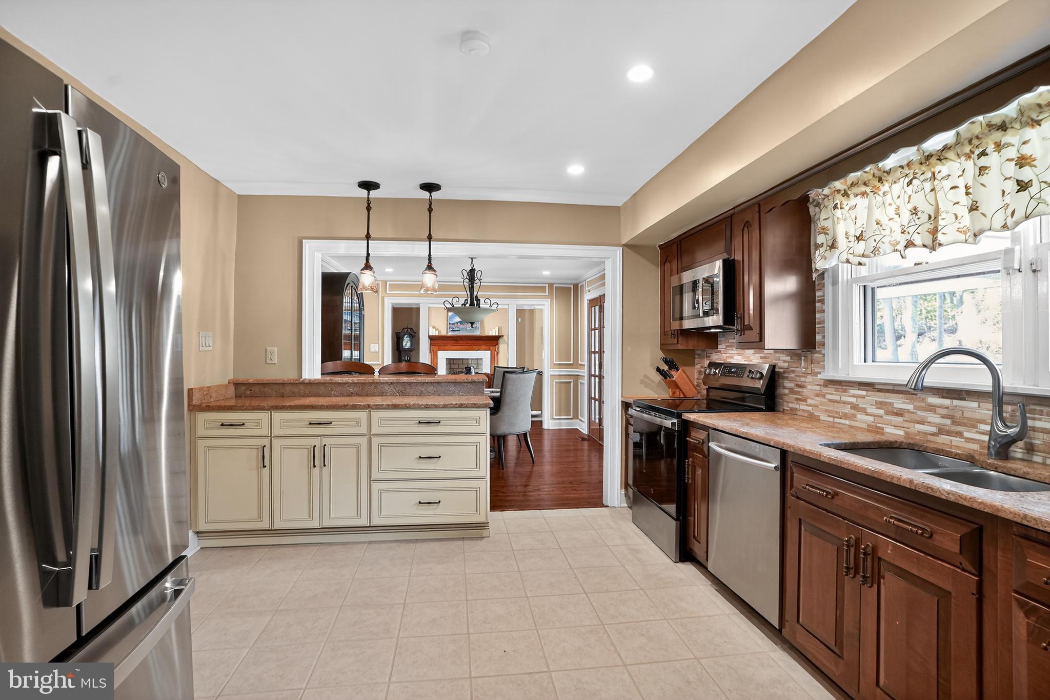 1013 Glen Road Wallingford, PA 19086 - Photo 26 of 45 a kitchen with stainless steel appliances granite countertop a refrigerator oven a sink dishwasher and white cabinets next to a window