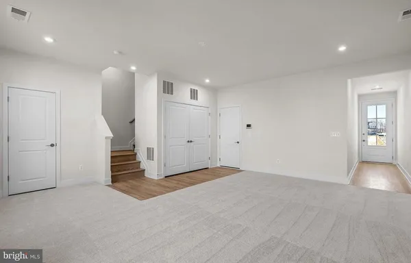 a view of an empty room with wooden floor and stairs