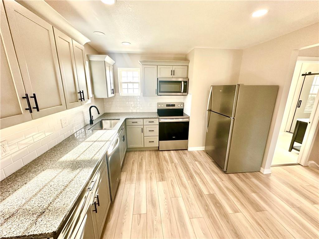 197 West Main Street, Unit 2 Uniontown, PA 15401 - Photo 7 of 13 a large kitchen with a refrigerator a sink and dishwasher a stove top oven with wooden floor