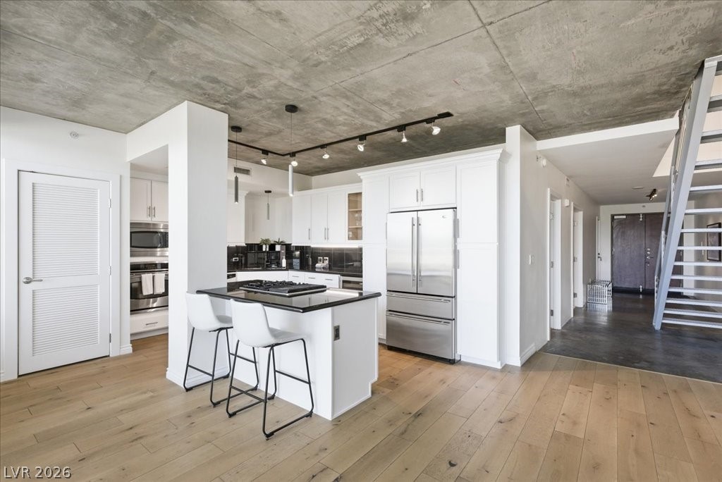 360 East Desert Inn Road, Unit 604 Las Vegas, NV 89109 - Photo 20 of 28 A contemporary kitchen design with bright cabinetry and a practical island, featuring a striking concrete ceiling.