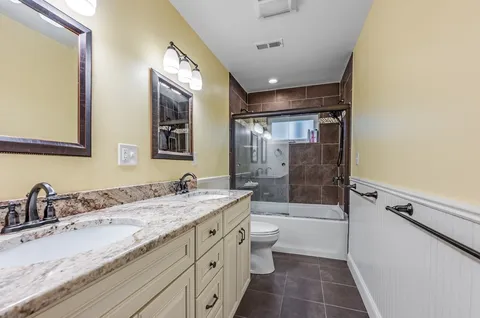 a bathroom with a granite countertop sink a toilet a mirror and shower