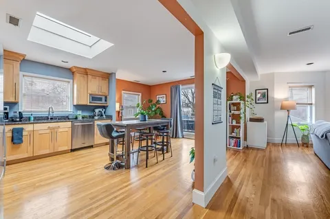 a kitchen with stainless steel appliances wooden floor dining table and chairs
