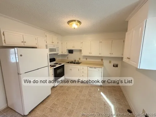 a kitchen with a refrigerator a stove top oven and white cabinets
