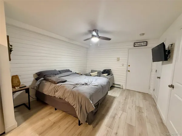 a spacious bedroom with a bed and a flat tv screen on a dresser