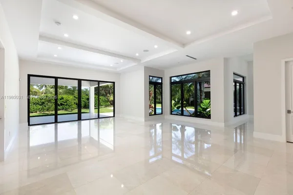 a living room with furniture large windows and wooden floor