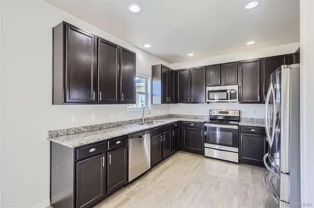 a kitchen with stainless steel appliances granite countertop refrigerator a sink a stove top oven and a center island