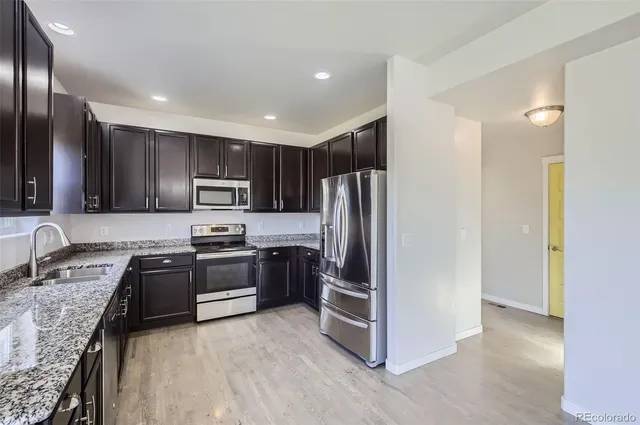 a kitchen with granite countertop a refrigerator stove and sink