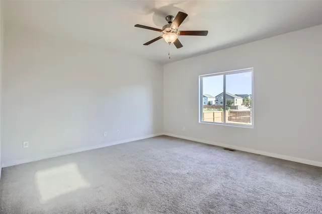an empty room with a window and a fan