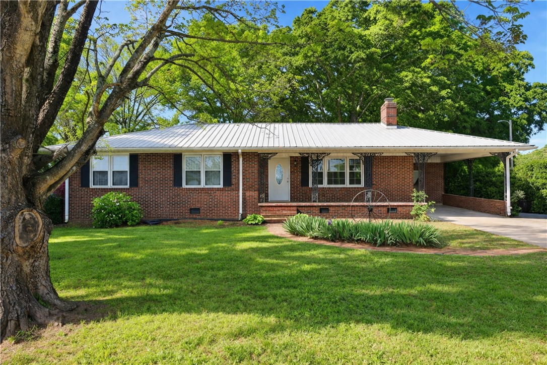 This charming residence features a classic brick exterior and a lush, verdant lawn.