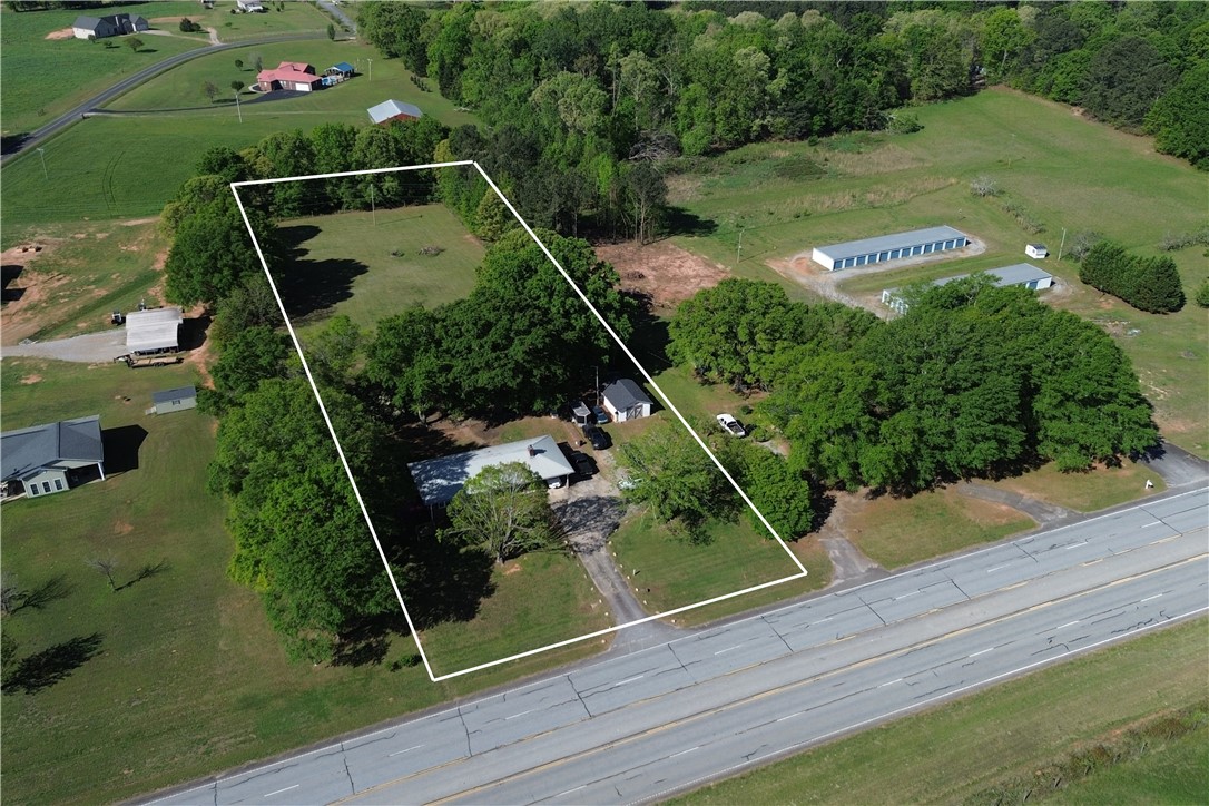 9432 Highway 81 Iva, SC 29655 - Photo 19 of 19 An expansive aerial view showcases a verdant property bordered by mature trees and a nearby road.