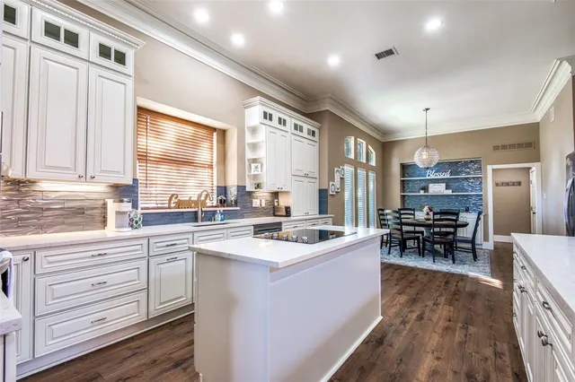 a kitchen with stainless steel appliances kitchen island granite countertop a stove top oven a sink a dining table and chairs with wooden floor