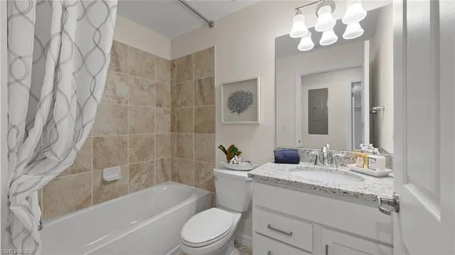 a bathroom with a granite countertop bathtub sink vanity mirror and toilet