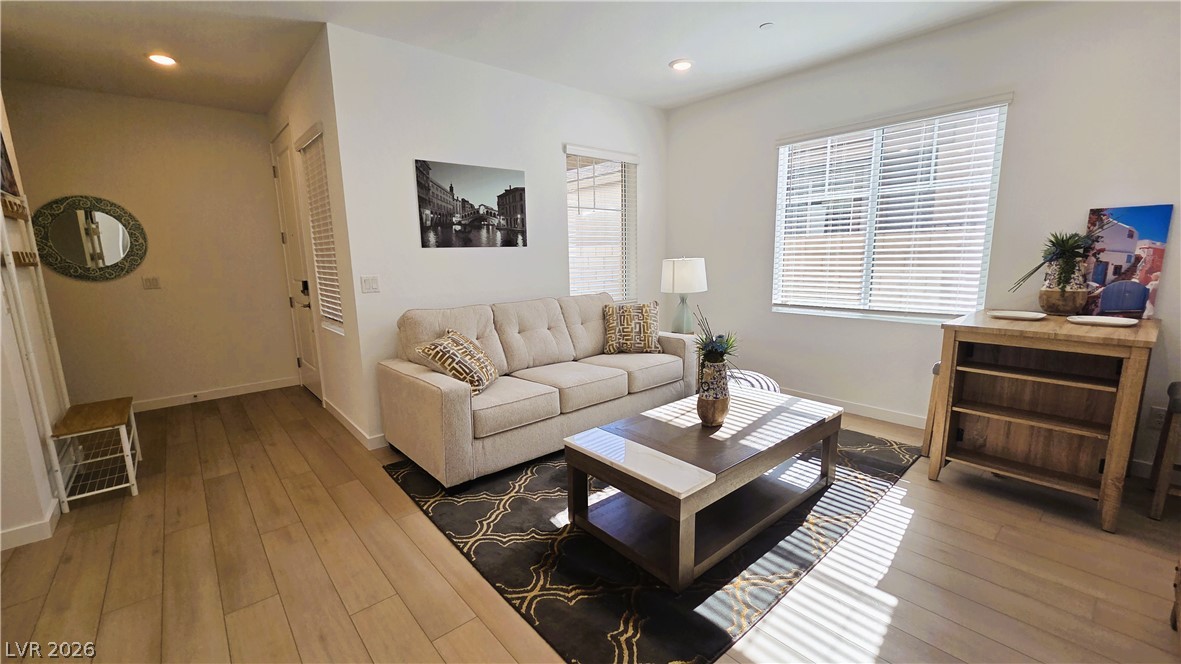 509 Arthur Pointe Street Henderson, NV 89011 - Photo 4 of 12 Sun-filled living area features natural wood flooring and a stylish area rug, creating an inviting atmosphere.