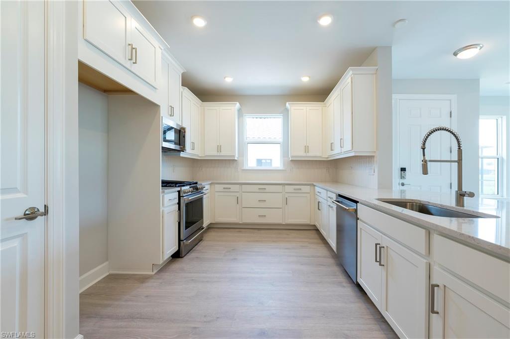 15633 Gavello Street Naples, FL 34114 - Photo 16 of 37 a kitchen with a white cabinets stove and sink