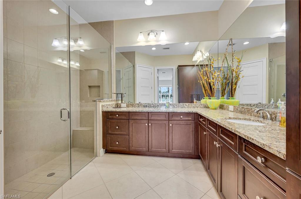 6553 Dominica Drive, Unit 101 Naples, FL 34113 - Photo 11 of 27 a bathroom with a granite countertop sink a large mirror and a shower