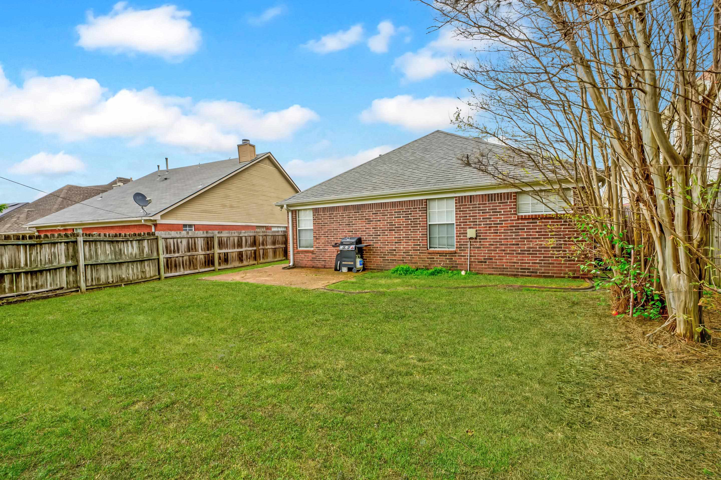459 North Ericson Road Memphis, TN 38018 - Photo 21 of 27 The fenced backyard is spacious and ready for summer barbecues or playtime, with a patio area perfect for outdoor living.
