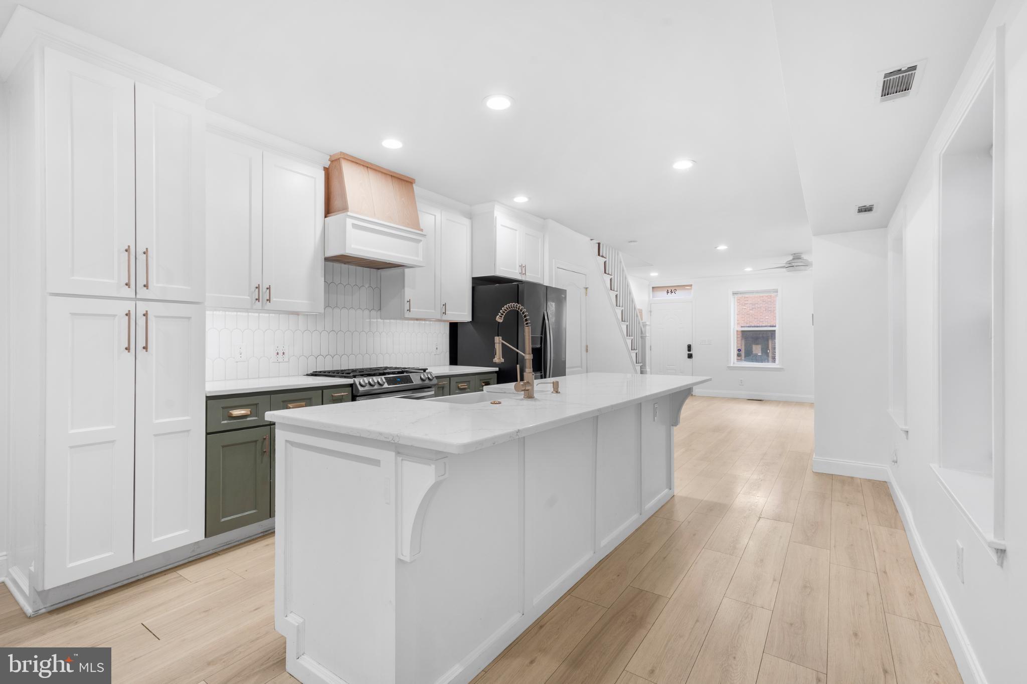 944 North Randolph Street Philadelphia, PA 19123 - Photo 13 of 26 a kitchen with kitchen island a stove a sink a refrigerator and white cabinets with wooden floor