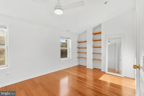 a view of empty room with wooden floor and fan