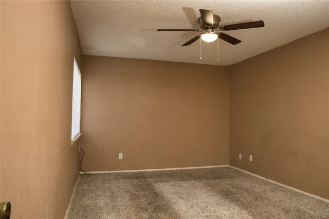 an empty room with a ceiling fan and a fan