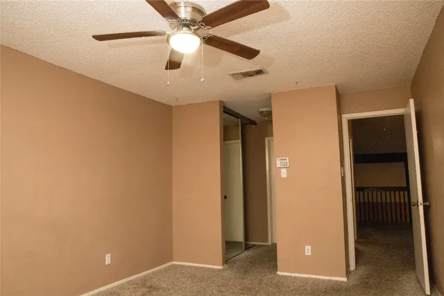 an empty room with closet and a ceiling fan
