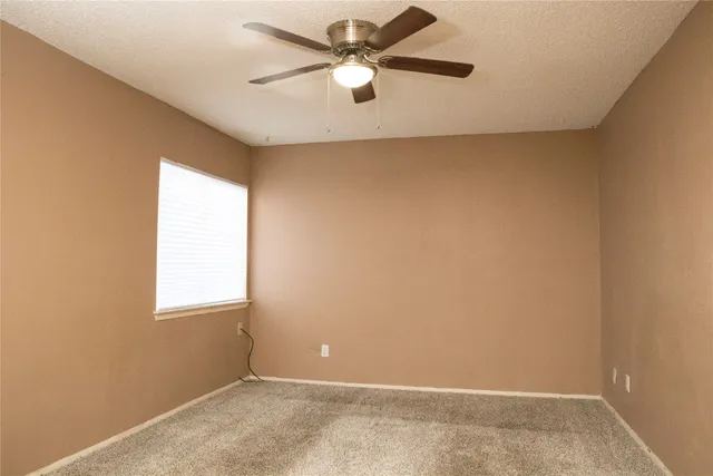 an empty room with a window and a ceiling fan