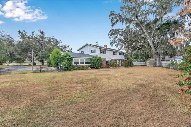 a view of a white house with a small yard and wooden fence