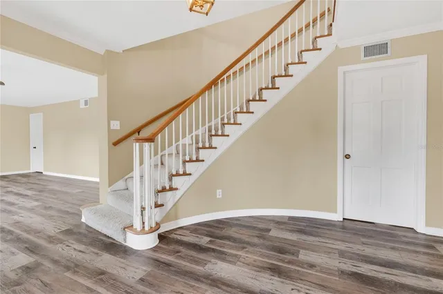 a view of empty room with wooden floor and fan