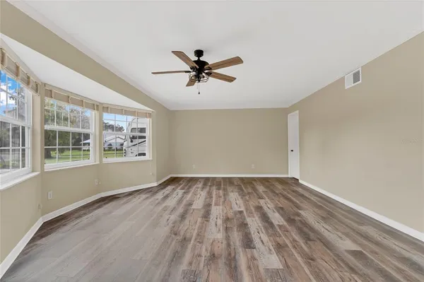 a view of an empty room with a window and wooden floor