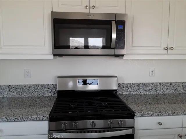 a kitchen with granite countertop white cabinets and a stove