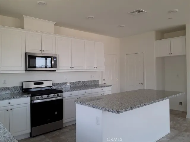 a kitchen with granite countertop white cabinets and stainless steel appliances