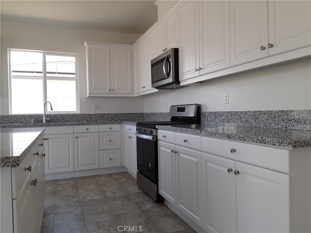 21108 Bison Mesa Road Riverside, CA 92507 - Photo 7 of 45 a kitchen with granite countertop white cabinets stainless steel appliances and window