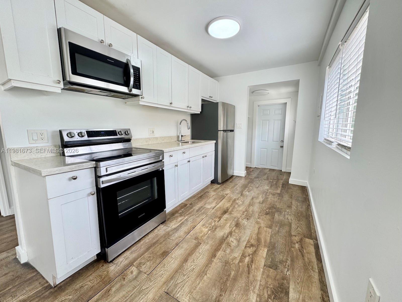 929 Southwest 12th Avenue, Unit 929 Miami, FL 33130 - Photo 8 of 18 a kitchen with stainless steel appliances granite countertop a stove microwave and sink