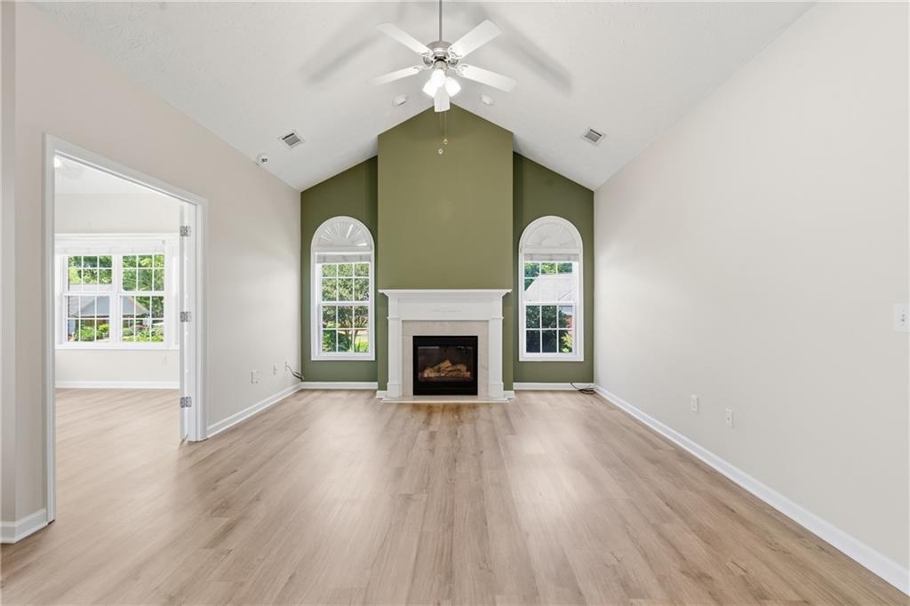 4533 Caleb Crossing, Unit 18 Powder Springs, GA 30127 - Photo 4 of 24 an empty room with windows fireplace and wooden floor